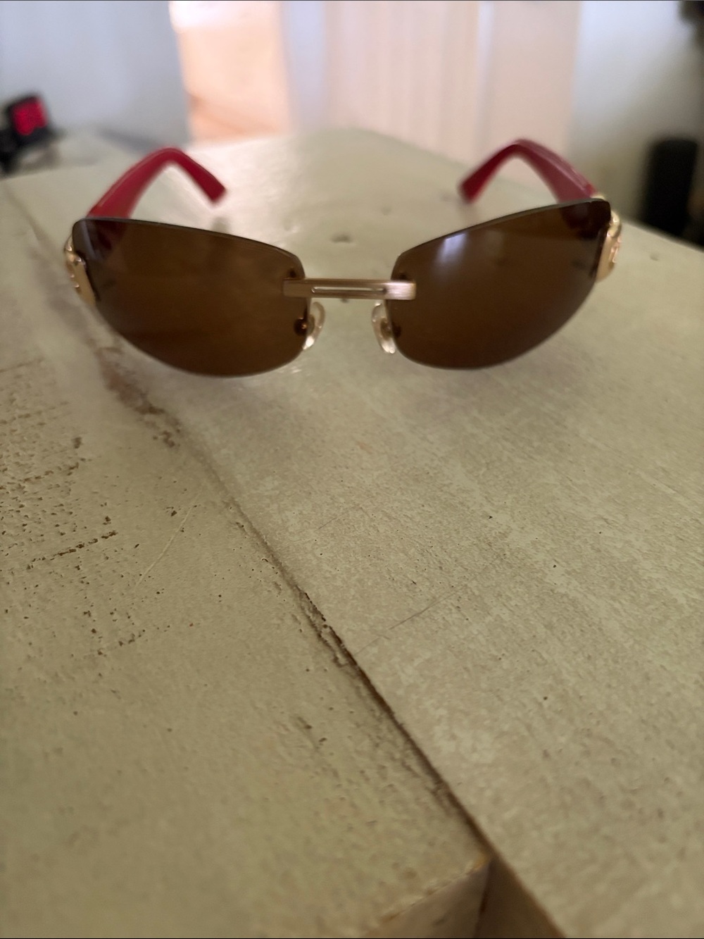Rimless Brown Lens Sunglasses with Red Arms and Gold Accents
